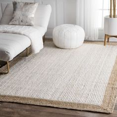 a living room area with a white couch and large rug on top of the floor