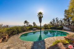 the pool is surrounded by stone steps, and there are palm trees in the background