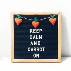 a sign that says keep calm and carrot on hanging from a string with hearts attached to it