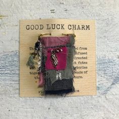 a piece of cloth with some beads on it and a tag that says good luck charm