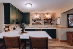 a kitchen with green cabinets and white counter tops, brown leather chairs and wooden flooring