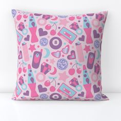 a pink and blue pillow with various items all over it on top of a white surface