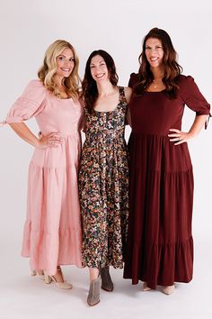 three women standing next to each other in dresses