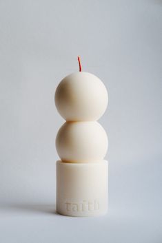 a white candle with the word faith on it sitting in front of a gray background