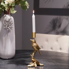 a gold bird figurine sitting on top of a table next to a candle