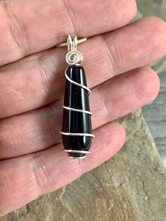 The classic beauty of this long smooth rounded teardrop black onyx necklace is stunning. The deep black color of the stone is beautiful in its simplicity. I chose to enhance this gorgeous gem with a minimalist spiral silver wire design to let the natural beauty shine. Black onyx is an alternate birthstone for July, making this a great gift. *Size 1.5 x .4 inches *Genuine black Onyx Gemstone *Sterling Silver Plated *Includes a Sterling Silver plated chain with a lobster clasp and your choice of l Black Teardrop Pendant For Jewelry Making, Black Oval Pendant Minimalist Jewelry, Minimalist Black Wire Wrapped Necklace, Minimalist Black Oval Pendant Jewelry, Modern Black Long Drop Jewelry, Minimalist Black Teardrop Pendant Necklace, Black Onyx Pendant, Wire Wrap Jewelry Designs, Wire Design