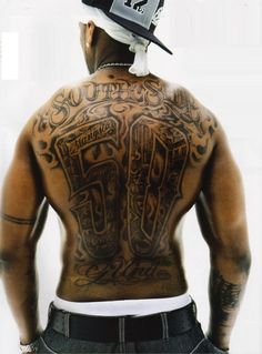 the back of a man with tattoos and a hat on his head is seen from behind