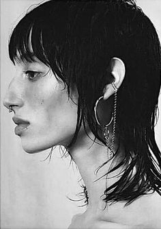 a black and white photo of a woman's face with earrings on her ear