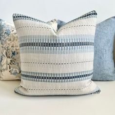 three blue and white pillows sitting on top of a bed