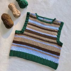 a crocheted sweater next to two balls of yarn