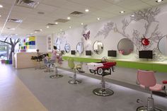 a salon with chairs and mirrors on the wall, people sitting at their desks