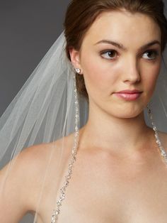 a woman in a wedding dress wearing a bridal veil and diamond necklace with pearls