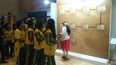 a group of young people standing next to each other in front of a wall with information on it