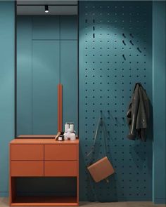 an orange dresser and mirror in a blue room with pegs on the wall behind it