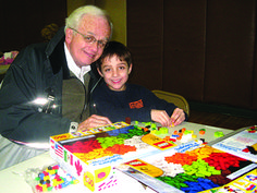 an older man and young boy are sitting at a table with legos on it