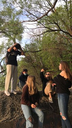 several people are standing on top of a rock and one person is looking at something in the distance