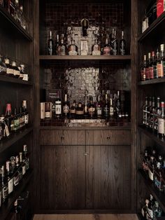 the shelves are full of liquor bottles and other items in this dark wood - paneled room