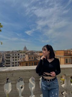 a woman standing on top of a building next to a fence and looking at the sky