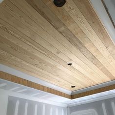 an unfinished ceiling with wood planks and a light fixture