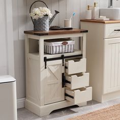 a white kitchen with an open door and storage drawers on the bottom shelf, next to a sink