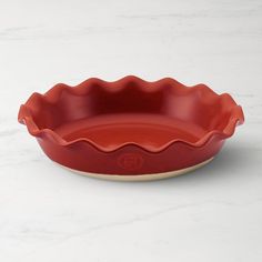 a red ceramic dish on a white marble surface