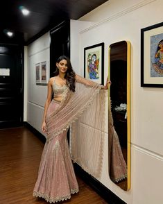 a woman standing in front of a mirror with her arms on the wall and wearing a sari