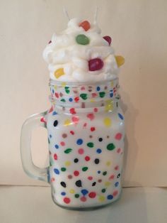 a glass jar filled with white frosting and colorful candies