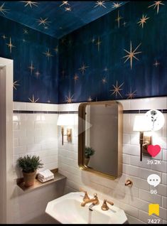 a bathroom with stars painted on the ceiling and white tile walls, along with a gold framed mirror