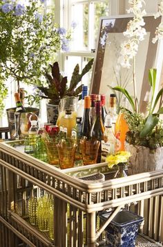 a table with lots of bottles and glasses on it's top, sitting in front of a window