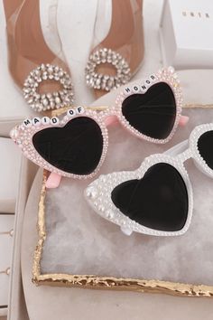 two pairs of heart shaped sunglasses sitting on top of a white box next to each other