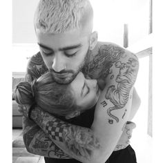 a man and woman hugging each other with tattoos on their arms