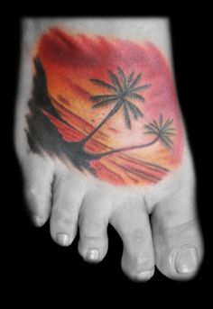 a person's foot with a palm tree and sunset tattoo on the bottom of it