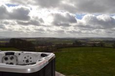 a hot tub sitting on top of a cement slab next to a lush green field