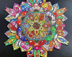 an intricately colored paper art piece on a black surface with lots of different colors