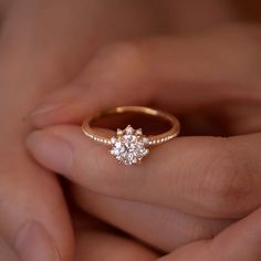 a woman's hand holding an engagement ring with two diamonds on top of it