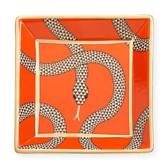 an orange and black square plate with a snake design on the front in gold trim