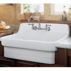 a large white sink sitting on top of a counter next to a wooden cabinet and window