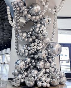 a bunch of silver balls are stacked on top of each other in the middle of a room