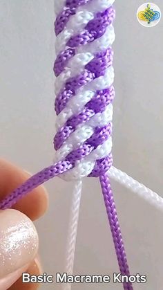 someone is holding an object with purple and white yarn