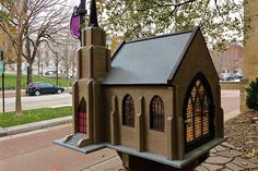 a small church made out of concrete on the sidewalk