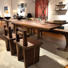 a large wooden table with benches in front of it and pictures on the wall behind it