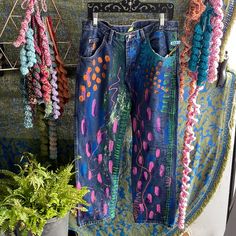 jeans hanging up on a rack next to potted plants