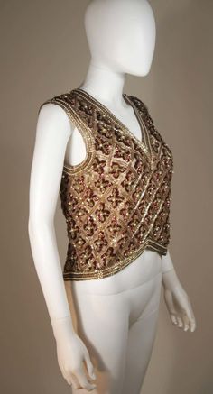 For Sale on 1stDibs - This Galanos blouse is composed of a beaded and sequin appliqued silk, in gold and burgundy hues. The top features a 3-dimensional beading technique. There Fitted V-neck Top With Mirror Work, Elegant V-neck Tops For Reception, Luxury Embellished Tops For Formal Occasions, Luxury Embellished Formal Top, Bollywood Style Hand Embellished Festive Tops, Festive Bollywood Hand Embellished Tops, Bollywood Style Embellished Party Tops, Bollywood Style Embellished Top For Reception, Traditional Embellished Party Top