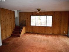 an empty living room with wood paneling and stairs