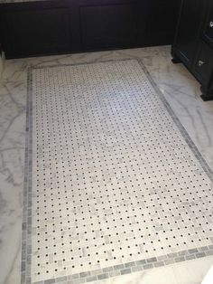 a bathroom with white marble and black cabinetry on the walls, along with a gray tiled floor