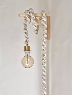 a light bulb hanging from a wooden beam with rope attached to it and an object in the background