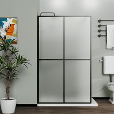 a bathroom with a toilet, shower and plant in the corner on the floor next to the bathtub