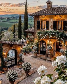 a beautiful house with lots of flowers in the front yard and trees on the other side