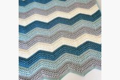 a crocheted blanket with blue and white waves