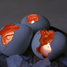 three eggs with candles in them sitting on some ice